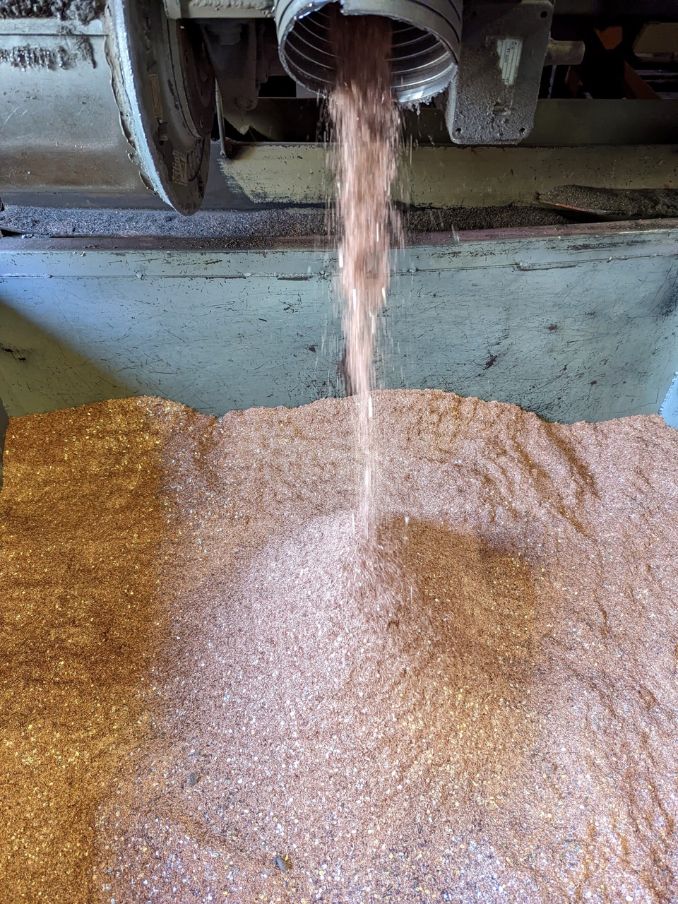Copper chops falling from a wire granulator into a collection bin