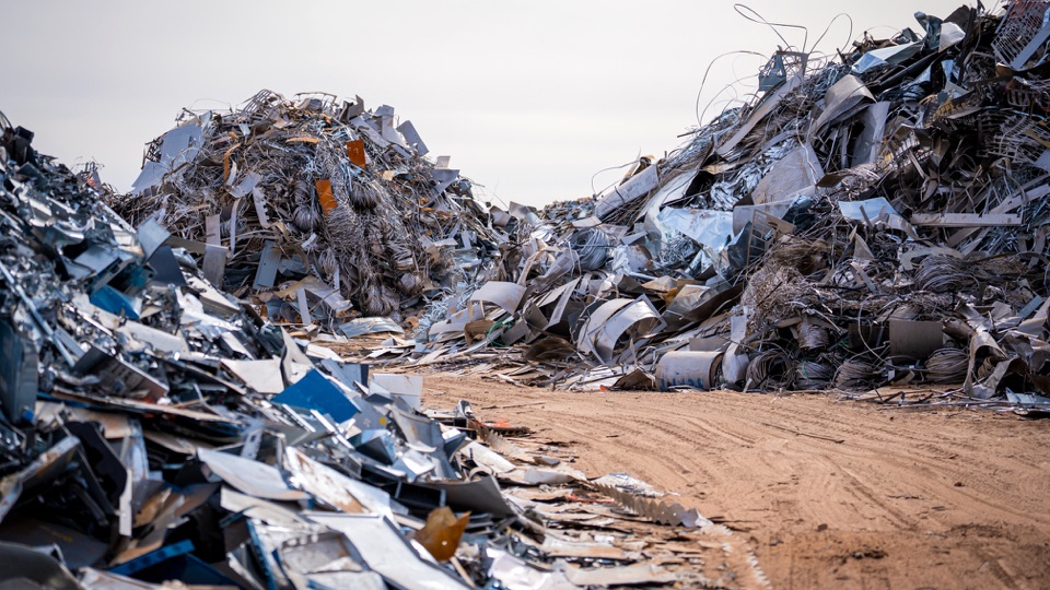 Scrap metal arranged in piles alongside a yard lane